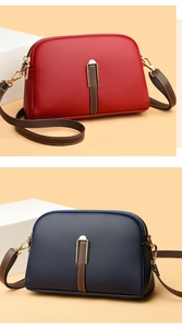Detail of red and navy shell crossbody bags in lychee leather with gold hardware accent