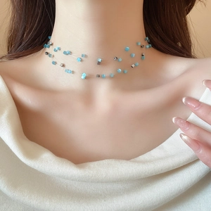 Vue rapprochée du collier en fil de pêche avec perles bleues et argentées sur le cou
