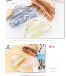 Detailed close-up of cloud-shaped acetate hair claws with sparkling rhinestone edges