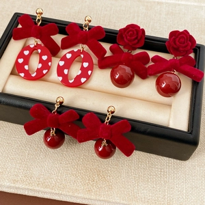 Drei dunkelrote Ohrringe mit beflockten Schleifen und Rosen in einer Schmuckbox