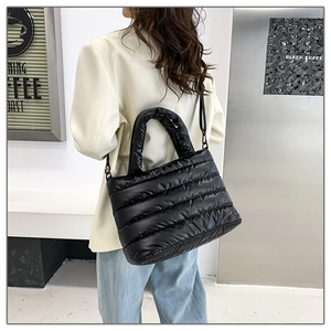 Close-up of black quilted puffer tote bag with glossy nylon finish and sturdy top handles