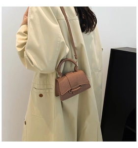 Détail d'un mini sac à main marron texturé avec poignée torsadée et bandoulière longue