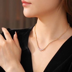 Elegantly worn gold necklace with curved pink gemstones on a model in black attire