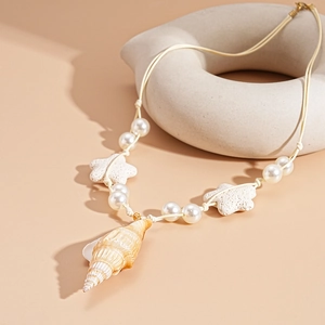 Detailed shot of ocean-style necklace with large conch shell and white pearls on beige rope