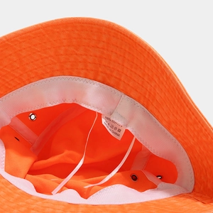 Détail du chapeau de soleil en coton orange fluo montrant la doublure et l'étiquette 100% coton