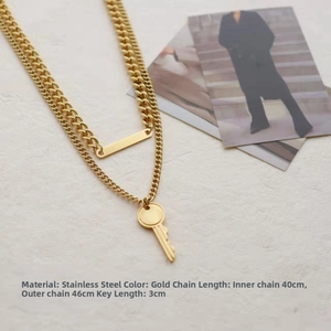 Detail of gold double-layered Cuban chain necklace with key pendant and steel bar