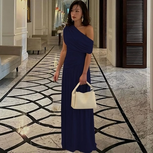 Detail of navy blue one-shoulder dress featuring elegant ruched waist and floor-length hem