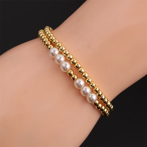Detail of double-layer stretch bracelet with gold plated beads and white pearls on wrist