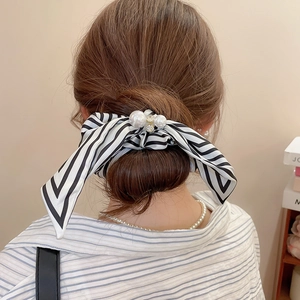 Detailed view of striped satin bow scrunchie with rhinestones and pearls on hair