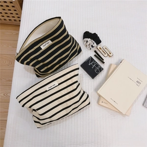 Flat lay of black striped cotton canvas makeup bags with zip closure and simple label