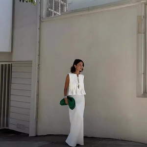 Elegant white sleeveless pleated top and long skirt set styled with a green clutch bag