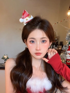 Close-up of red and white Christmas hat hair clip with glitter details on a model