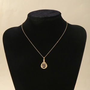 Detailed view of water drop gold pendant with Arabic script and inlaid cubic zirconia