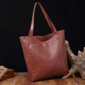 Détail de la grande poche avant sur un sac cabas vintage en cuir huilé marron sur bois