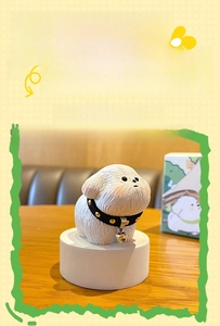 Close-up of white resin Bichon figurine with realistic fur texture and tiny metal bell