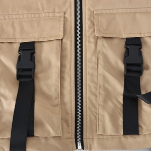 Detailed close-up of khaki utility vest featuring silver zipper and black plastic buckles
