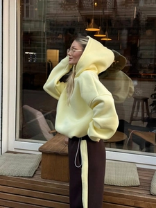 Dettaglio della felpa gialla oversize e pantaloni marroni con strisce laterali sportive