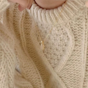 Minimalist 925 sterling silver gold necklace with an oval opal pendant worn on a beige sweater