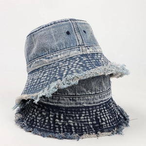 Dettaglio dei bordi sfrangiati sui cappelli bucket in denim lavato chiaro e scuro