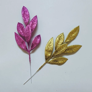 Dettaglio di foglie di pino artificiali glitterate oro e rosa per decorazioni natalizie