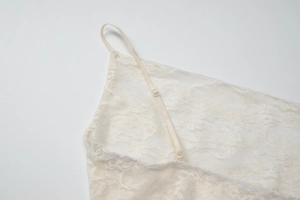 Detail of adjustable thin shoulder straps on a beige lace dress with floral patterns