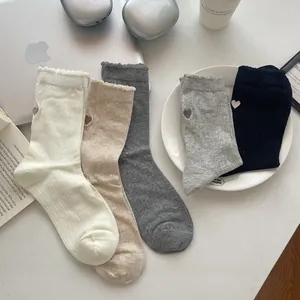 Detailed view of women's mesh socks with embroidered hearts and wavy cuffs in five colors
