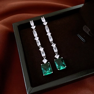 Detail of emerald cut green gemstone drop earrings with silver fringe in luxury jewelry box