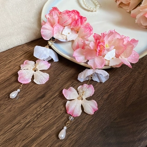 Détail d'une pince à cheveux fleur en soie rose avec de longs pompons perles sur assiette