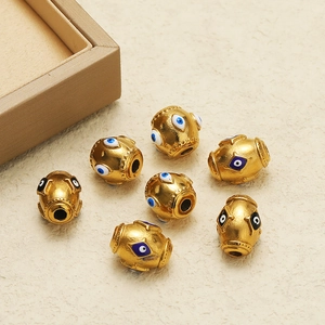 Macro view of golden evil eye beads with blue enamel detailing on a textured surface