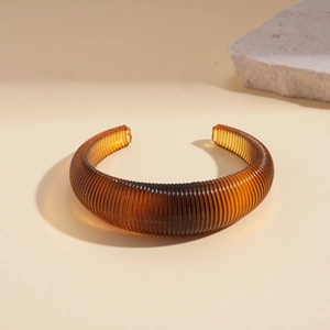 Macro shot of amber resin cuff bracelet featuring a detailed ribbed texture and retro style