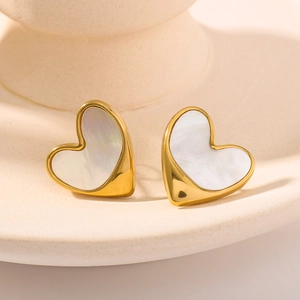Elegant gold heart earrings with white mother-of-pearl inlay on a ceramic tray