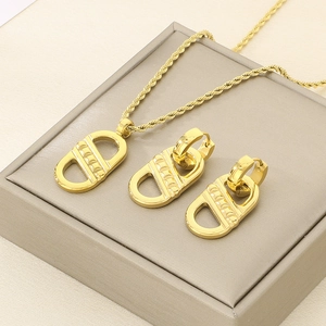 Golden teardrop jewelry set with necklace and earrings on light gray display