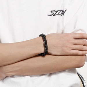 Close-up of matte black Cuban chain bracelet with textured dot surface worn on wrist