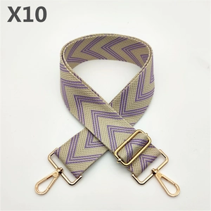 Close-up of beige fabric bag strap with purple herringbone pattern and gold metal hardware