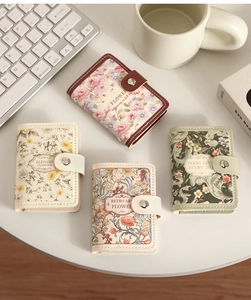 Macro shot of four floral credit card holders with snap buttons on a white desk