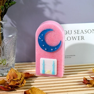 Dettaglio di un ornamento a castello lunare in resina rosa glitterata su vassoio di legno