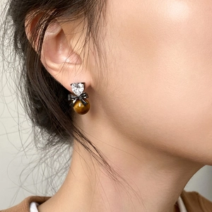 Detail of heart crystal and tiger eye stone earring with black bow on female model