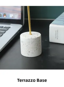 Detail of a cylindrical terrazzo base with golden metal rod for modern home desk decor