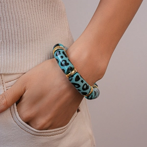 Close-up of blue leopard print acrylic bamboo link bracelet with gold metal spacers
