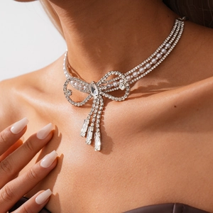 Close-up of bow necklace featuring layered pearls, sparkling rhinestones and crystal tassels
