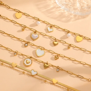 Elegant gold titanium heart bracelets with shell pearls and crystal accents on beige background