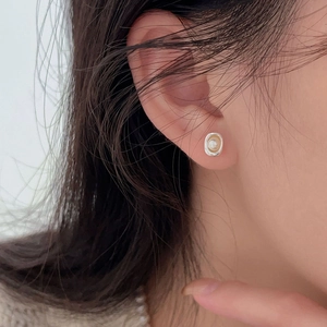 Gros plan d'une boucle d'oreille minimaliste en perle irrégulière argentée sur un modèle