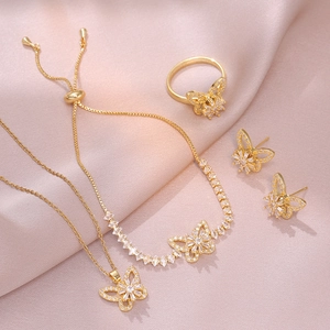 Elegant gold butterfly jewelry set including necklace, ring and earrings on pink silk