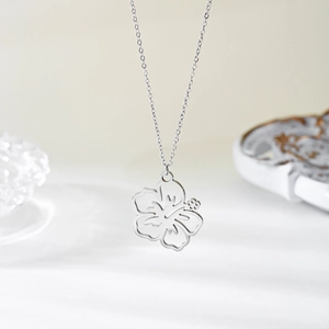 Macro detail of a silver-toned hollow flower pendant necklace with fine chain