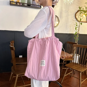 Detail of pink pleated cotton tote bag showing unique textured fabric and logo label