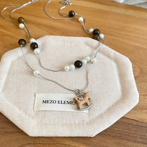 Détail du collier en œil de tigre et perles avec un pendentif cheval à bascule en bois