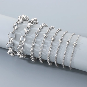 Variety of silver stainless steel curb and pearl bracelets displayed on grey pedestals