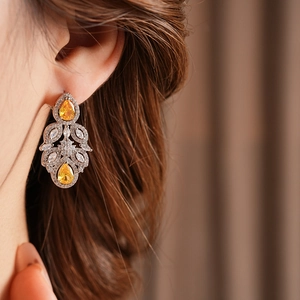 Detail of luxury teardrop flower earrings with yellow zircon and sparkling crystals