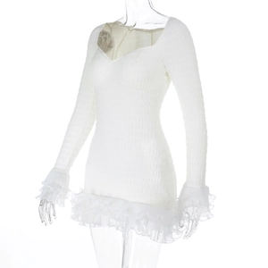 Detail of white long sleeve dress showing textured fabric and tiered ruffle hemline
