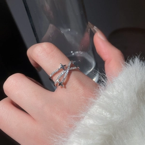 Gros plan d'une bague croisée en argent avec zircons et étoiles sur la main